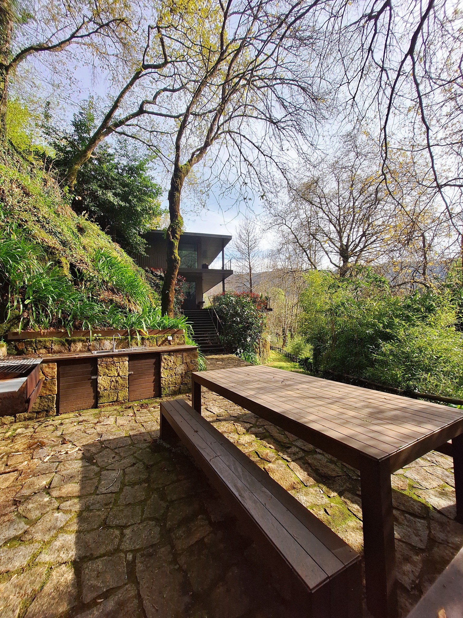 Outdoor stone terrace with long wooden table and seating at Runas Carqueijais in Gerês