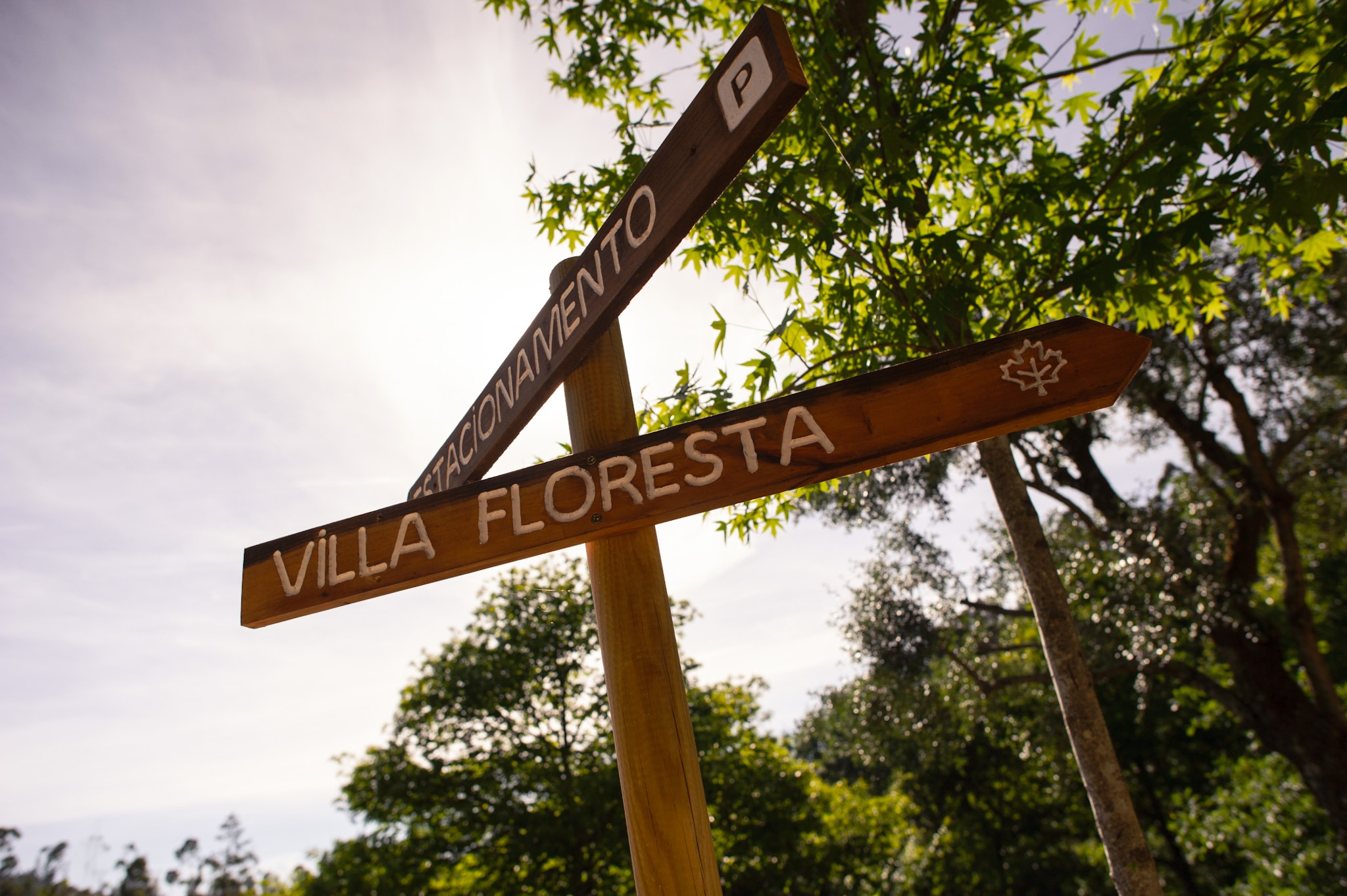 Wooden directional sign reading Villa Floresta surrounded by trees at Runas Carqueijais in Gerês