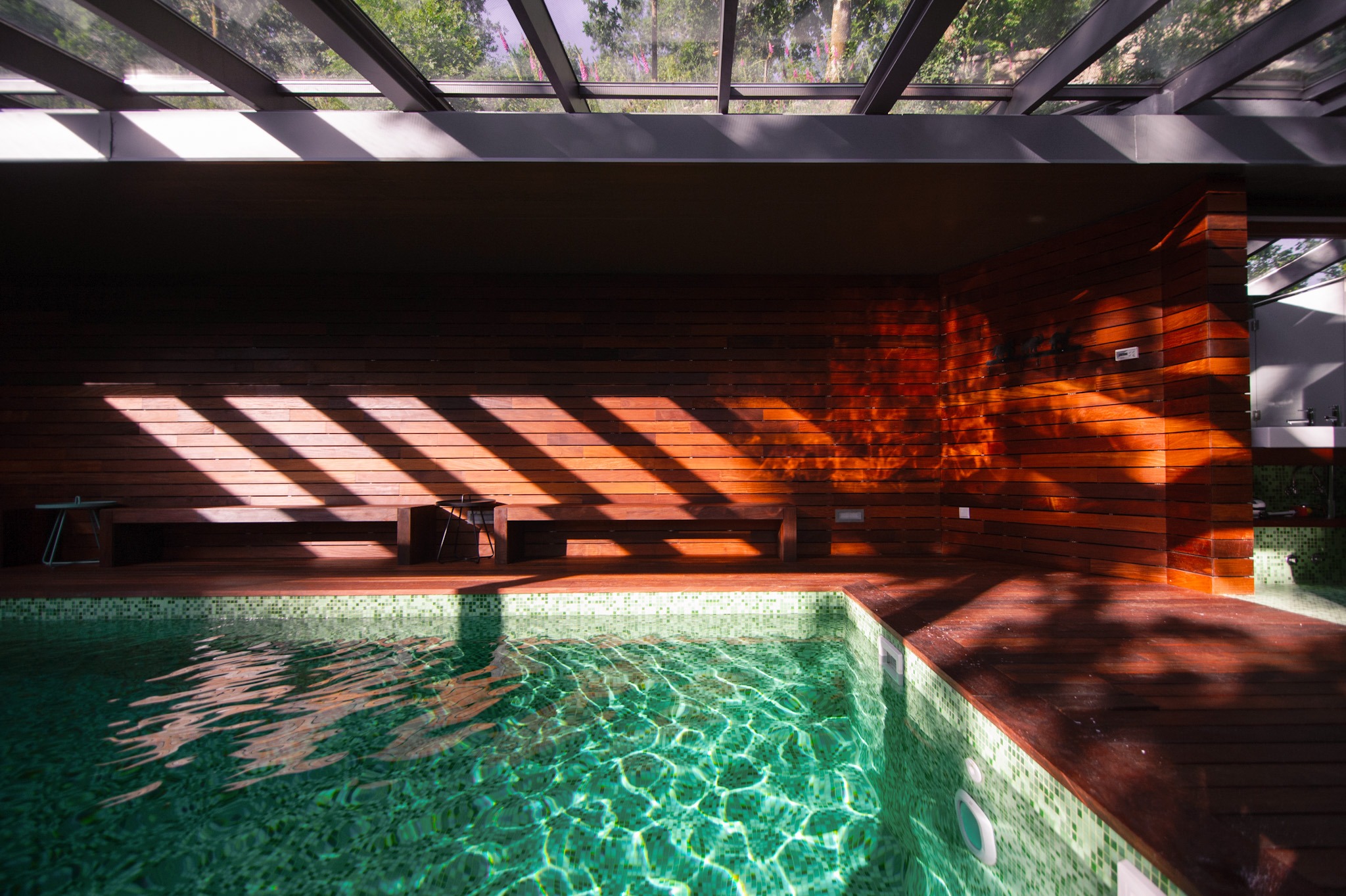 Indoor pool with turquoise water and sunlight casting shadows through glass at Runas Carqueijais in Gerês