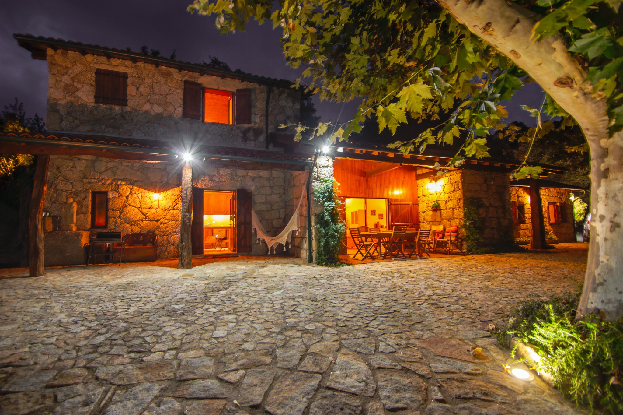 Stone house at night with warm lights and courtyard at Runas Carqueijais in Gerês