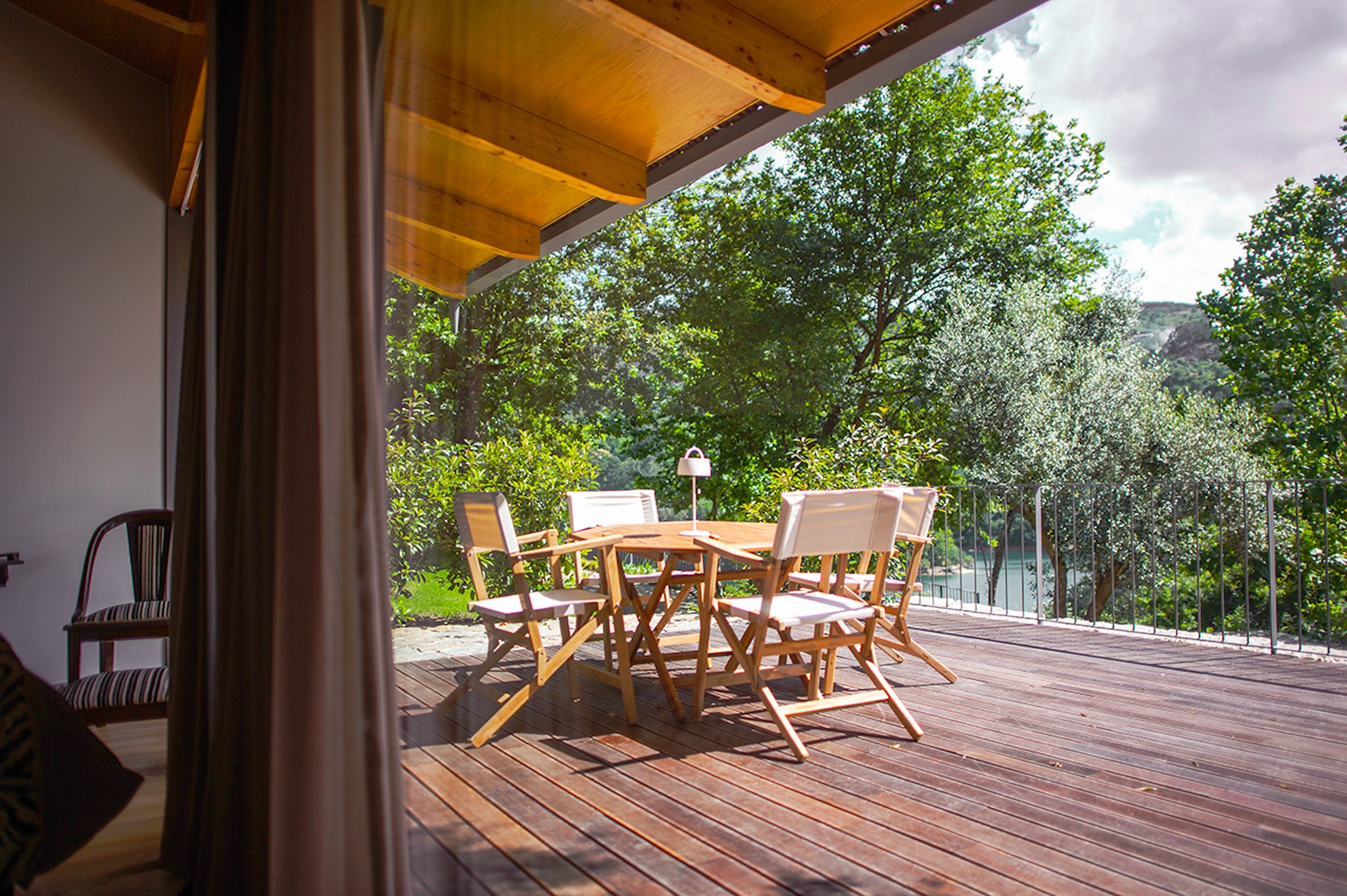 Wooden terrace with outdoor dining table and chairs at Runas Carqueijais in Gerês surrounded by trees