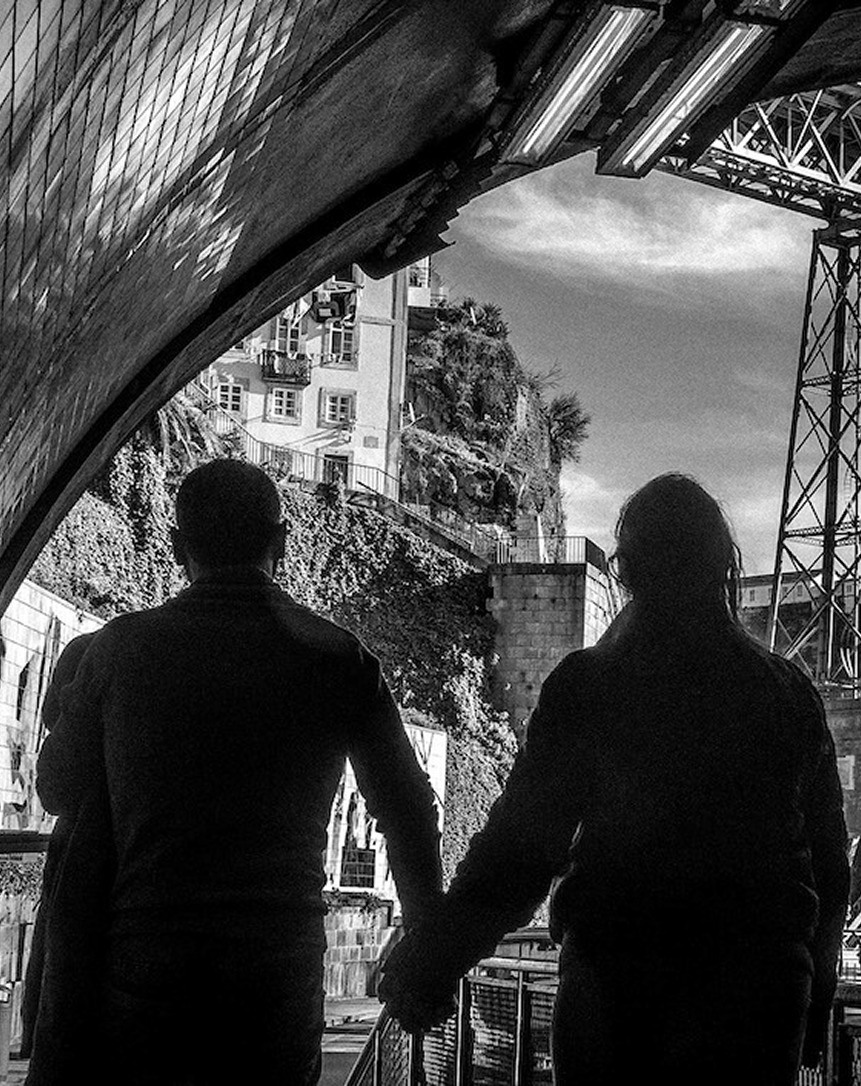 Silhouettes of people walking under structure