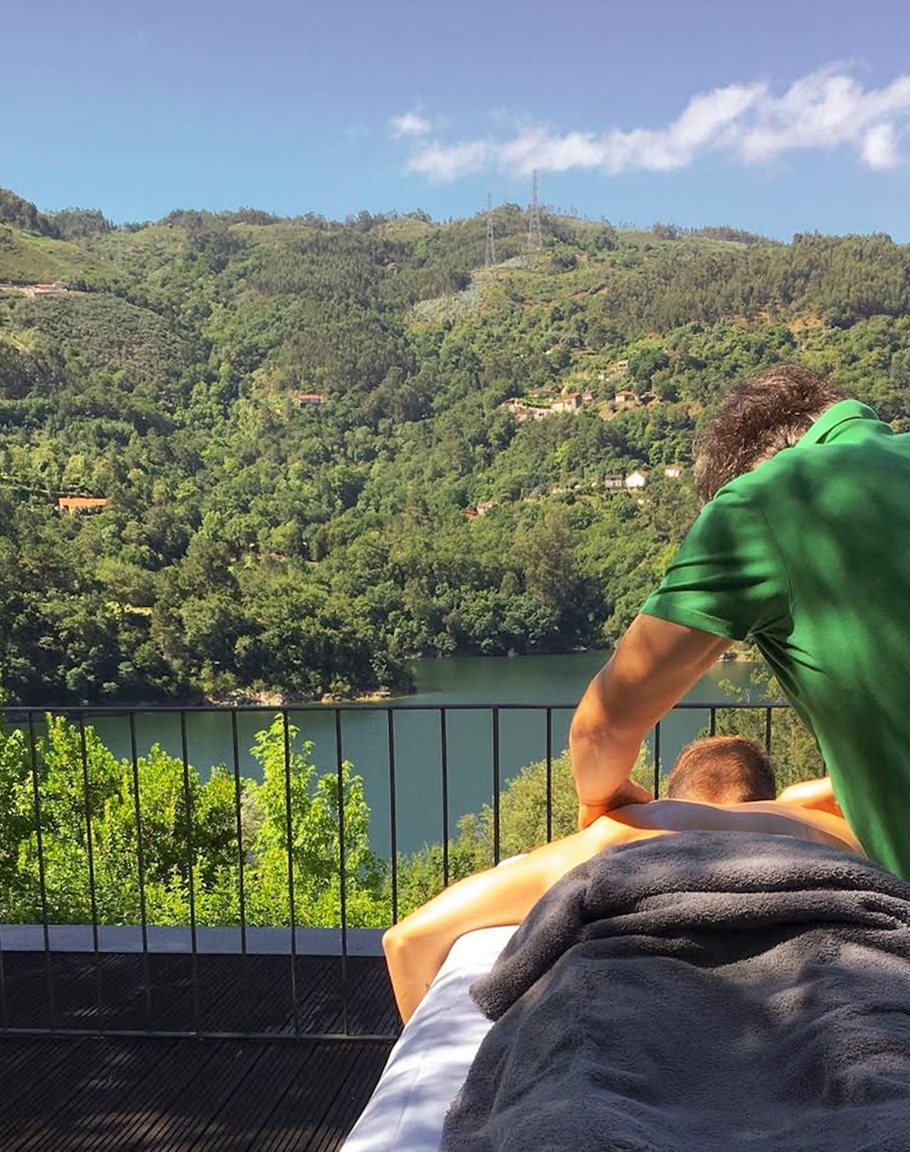 Person receiving a massage outdoors with a view over the lake and green hills